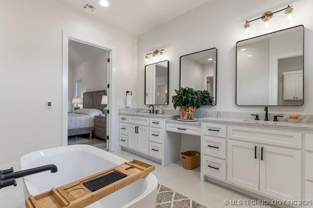 bathroom with tile patterned flooring, vanity, and a bath