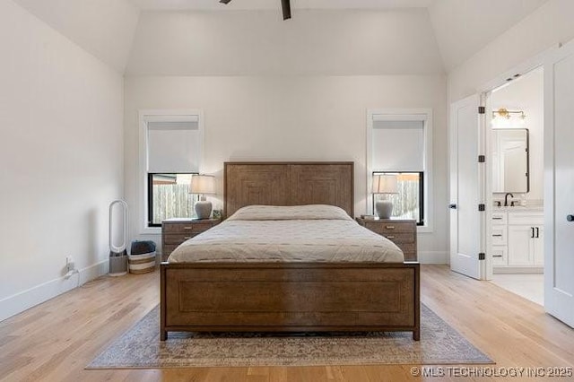 bedroom featuring ensuite bath, vaulted ceiling, and light hardwood / wood-style flooring