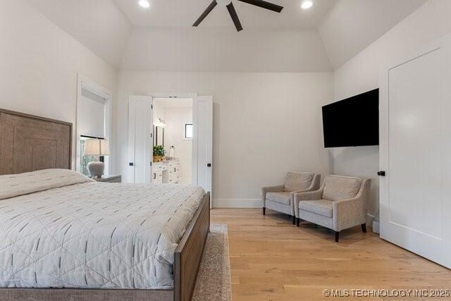 bedroom featuring vaulted ceiling, ensuite bathroom, ceiling fan, and light hardwood / wood-style flooring