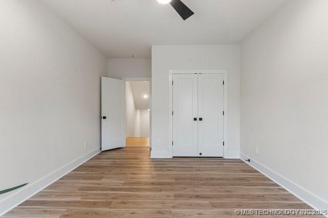 unfurnished bedroom featuring ceiling fan, light hardwood / wood-style floors, and a closet