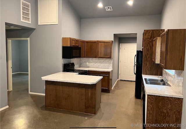 kitchen with sink, decorative backsplash, black appliances, and a towering ceiling