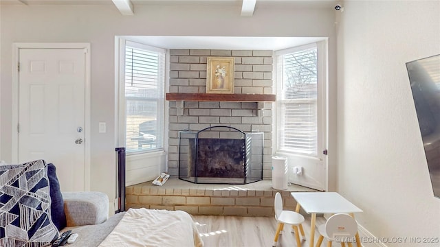 living room featuring wood-type flooring, a brick fireplace, and a wealth of natural light