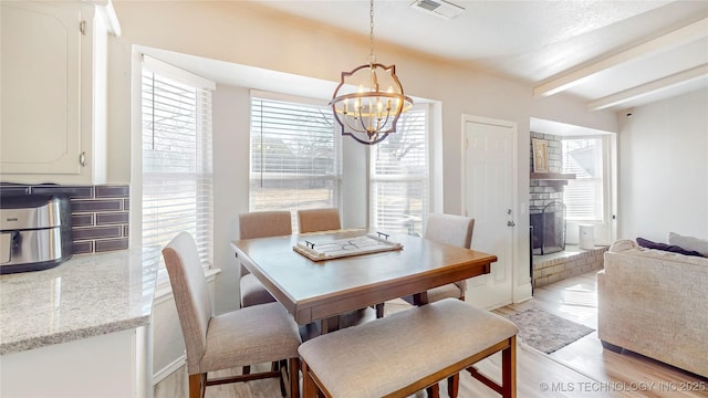 dining area with beam ceiling, a chandelier, and light hardwood / wood-style flooring