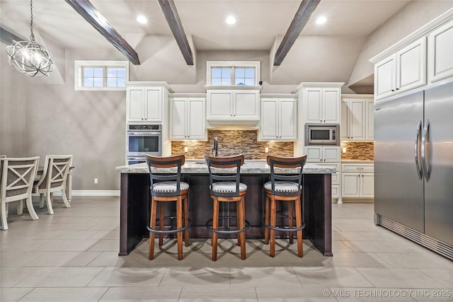 kitchen with a kitchen island with sink, built in appliances, white cabinets, and light stone counters