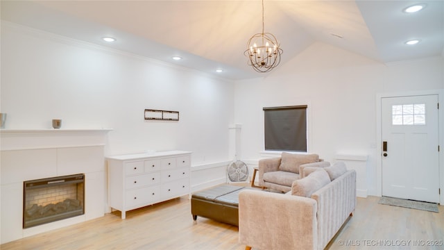 living room featuring a tiled fireplace, ornamental molding, lofted ceiling, and light hardwood / wood-style floors