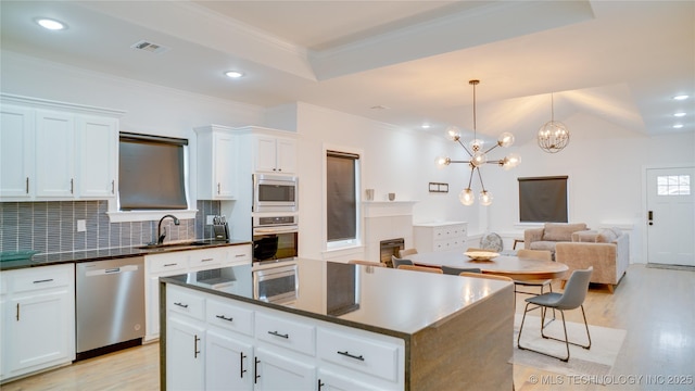 kitchen with a kitchen island, pendant lighting, white cabinetry, sink, and stainless steel appliances