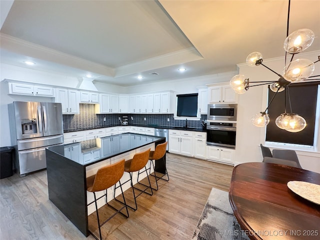 kitchen featuring hanging light fixtures, stainless steel appliances, a raised ceiling, and white cabinets