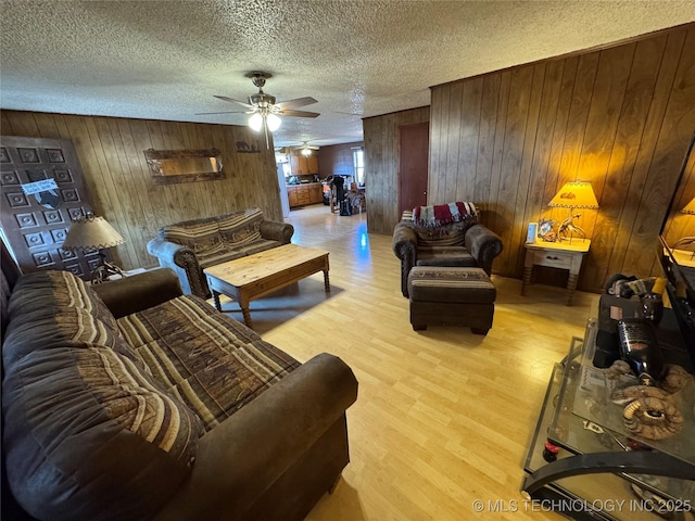 living room featuring ceiling fan, a textured ceiling, and light wood-type flooring