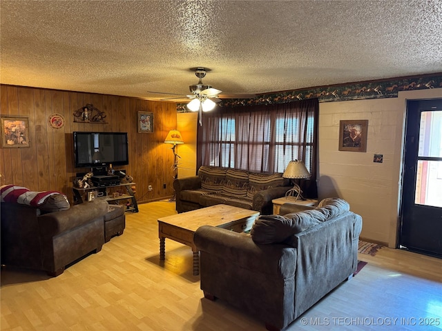 living room with ceiling fan, light hardwood / wood-style flooring, and a textured ceiling