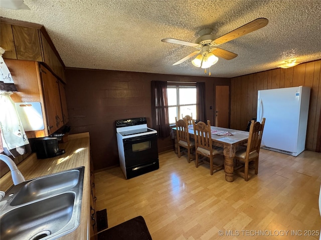 kitchen featuring white fridge, black electric range, sink, and light hardwood / wood-style flooring