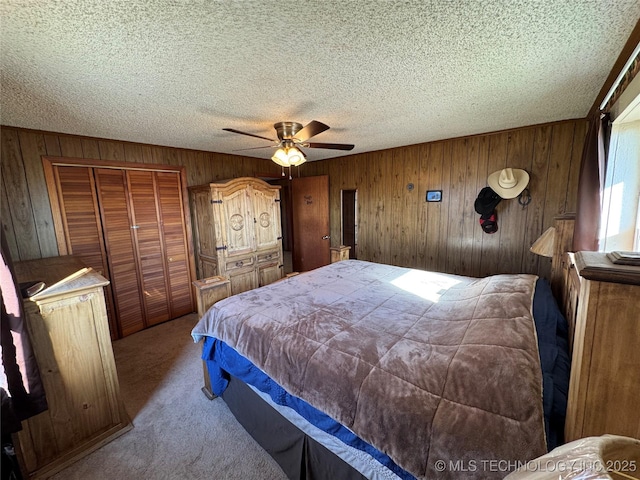 carpeted bedroom featuring ceiling fan, wooden walls, and a textured ceiling