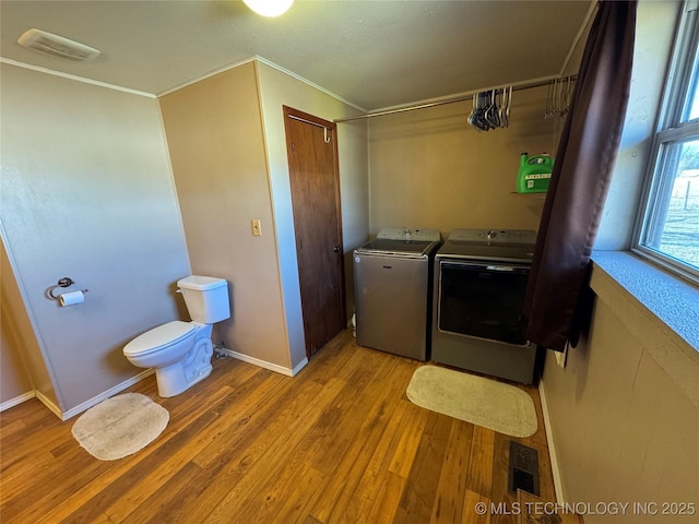 washroom with ornamental molding, washer and clothes dryer, and light hardwood / wood-style floors