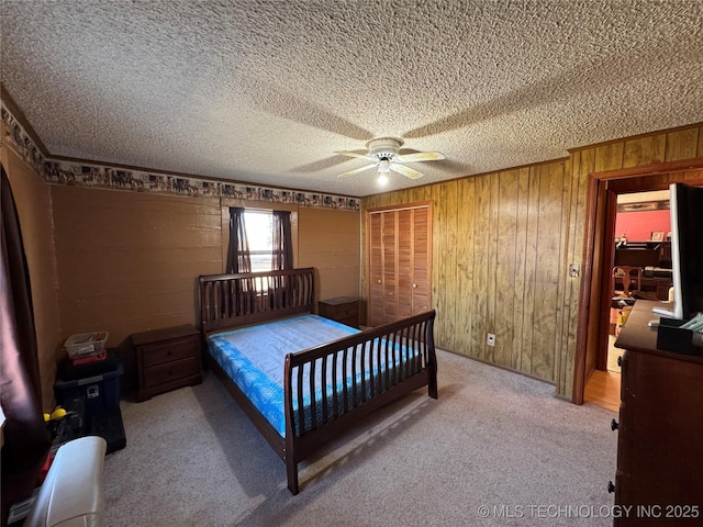 carpeted bedroom featuring ceiling fan, ornamental molding, wooden walls, and a textured ceiling