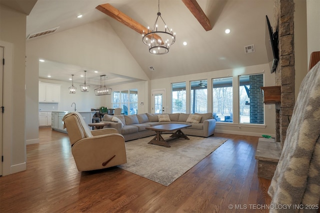 living room with sink, an inviting chandelier, wood-type flooring, high vaulted ceiling, and beamed ceiling