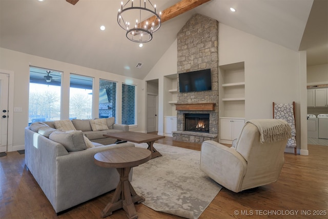 living room featuring a stone fireplace, washer and dryer, dark hardwood / wood-style floors, built in features, and beamed ceiling