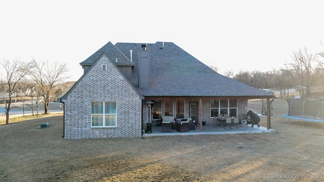 back of house featuring a lawn, a trampoline, and a patio area