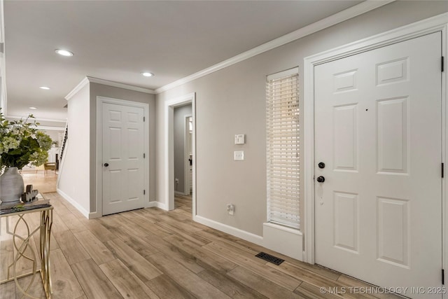 entryway with ornamental molding and light wood-type flooring