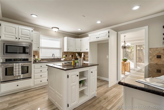 kitchen with stainless steel appliances, white cabinetry, a kitchen island, and sink