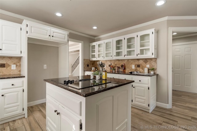 kitchen with white cabinetry, crown molding, a kitchen island, and dark stone countertops