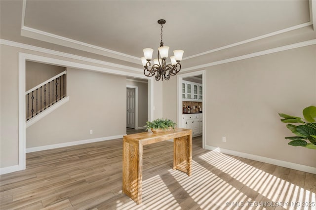 dining area with crown molding, hardwood / wood-style floors, a chandelier, and a tray ceiling