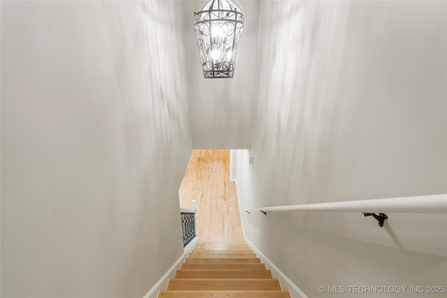 staircase with hardwood / wood-style floors and a notable chandelier