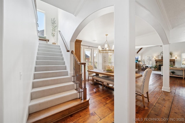 stairway featuring wood-type flooring, ornamental molding, and a chandelier