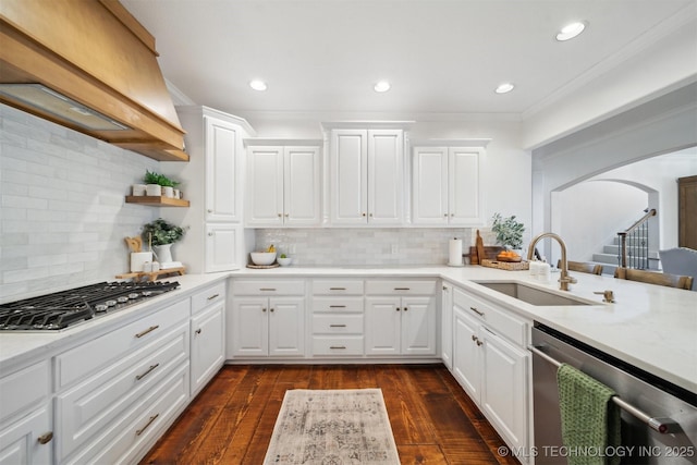 kitchen with custom range hood, white cabinets, and appliances with stainless steel finishes