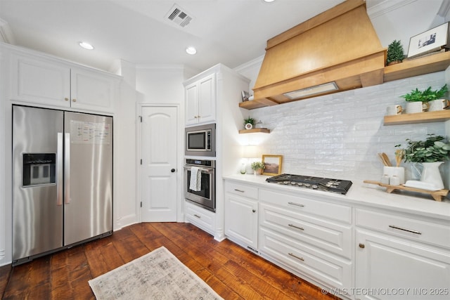 kitchen featuring appliances with stainless steel finishes, white cabinetry, dark hardwood / wood-style flooring, decorative backsplash, and custom range hood