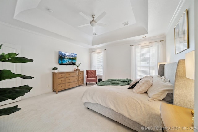 bedroom with crown molding, ceiling fan, a tray ceiling, and light carpet