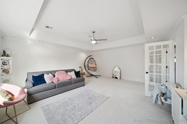 carpeted living room with ornamental molding, ceiling fan, and a tray ceiling