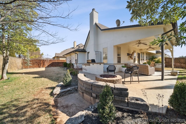 back of property with ceiling fan, a lawn, a patio area, and an outdoor living space with a fire pit