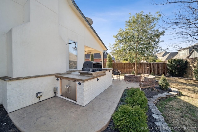 view of patio featuring exterior kitchen, area for grilling, and an outdoor fire pit