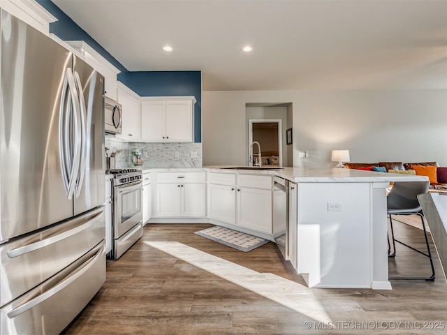 kitchen with sink, white cabinetry, a kitchen breakfast bar, kitchen peninsula, and stainless steel appliances