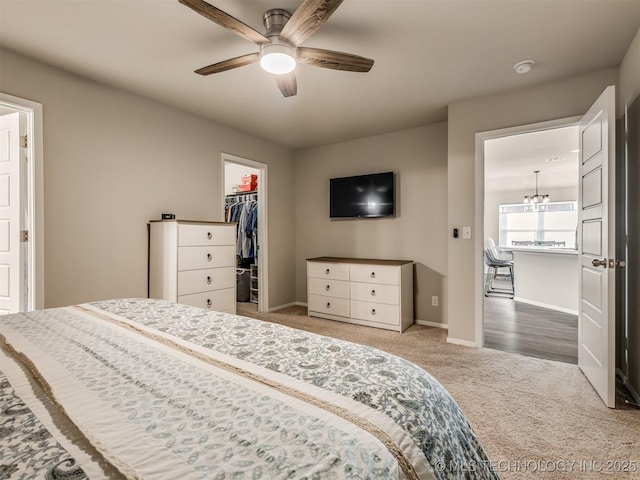 carpeted bedroom featuring a walk in closet, ceiling fan, and a closet