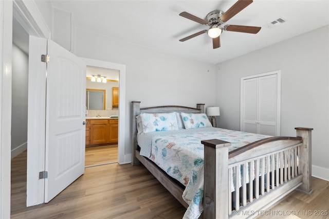 bedroom featuring ceiling fan, a closet, light hardwood / wood-style floors, and ensuite bath