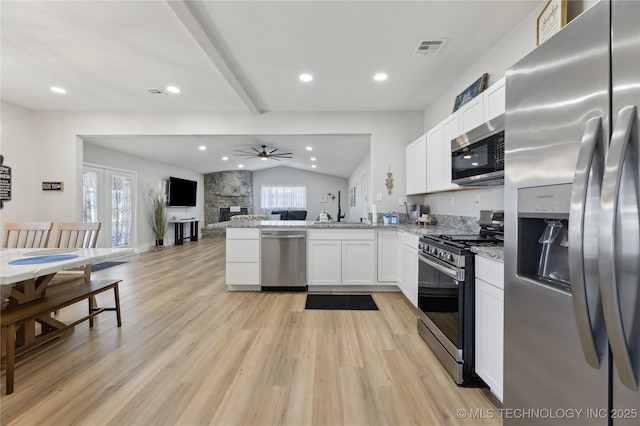 kitchen featuring vaulted ceiling with beams, light stone counters, appliances with stainless steel finishes, kitchen peninsula, and white cabinets