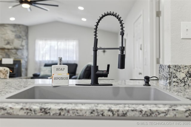 details featuring light stone counters, ceiling fan, and sink