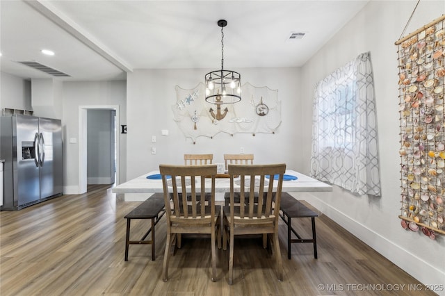 dining space with dark wood-type flooring and a notable chandelier