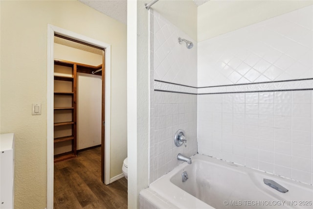 bathroom with hardwood / wood-style flooring, tiled shower / bath, a textured ceiling, and toilet