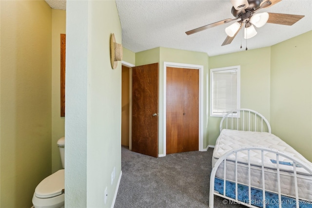 bedroom with dark colored carpet, ceiling fan, and a textured ceiling