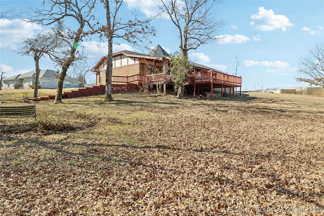 back of property featuring a deck and a lawn