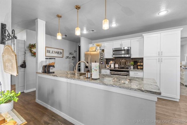 kitchen featuring light stone countertops, decorative light fixtures, stainless steel appliances, and white cabinets