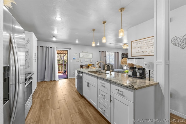 kitchen with white cabinetry, sink, stainless steel appliances, and stone counters