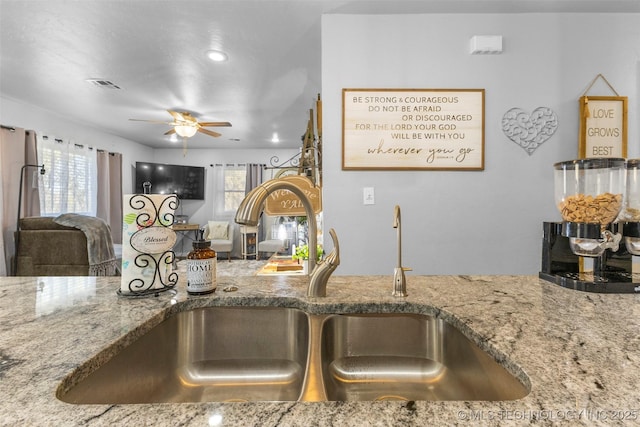 kitchen featuring stone counters, sink, and ceiling fan