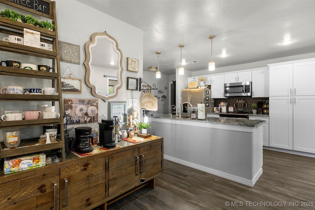 kitchen featuring stone counters, white cabinets, dark hardwood / wood-style flooring, hanging light fixtures, and stainless steel appliances