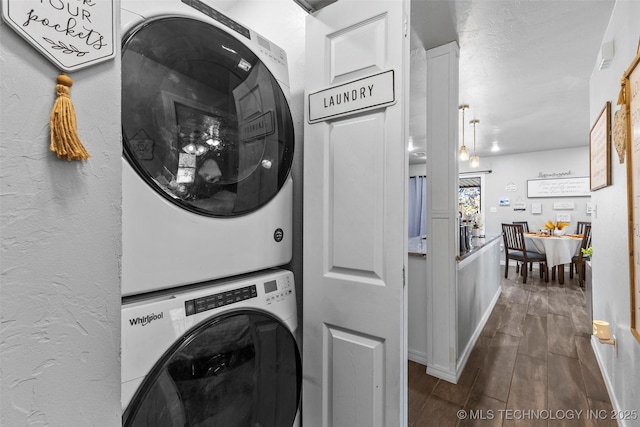 laundry room with dark hardwood / wood-style flooring and stacked washer and clothes dryer