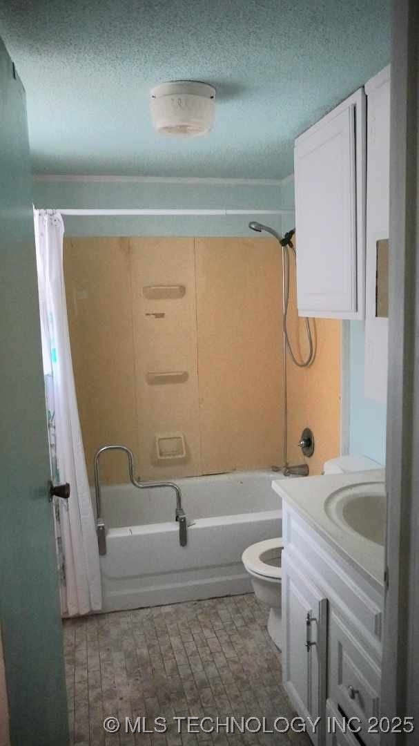 full bathroom with vanity, shower / tub combo, toilet, and a textured ceiling