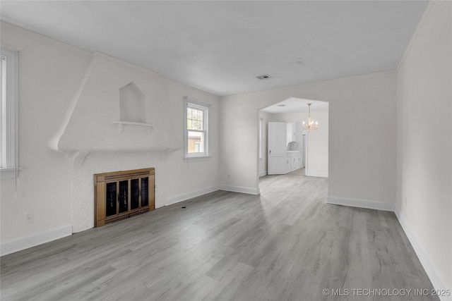 unfurnished living room featuring light wood-type flooring, an inviting chandelier, and a fireplace