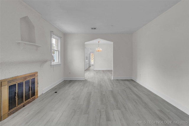 unfurnished living room featuring a chandelier and light wood-type flooring