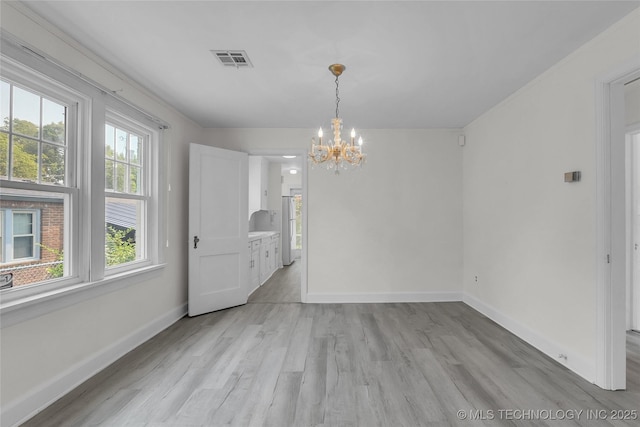 unfurnished dining area featuring an inviting chandelier and light hardwood / wood-style floors